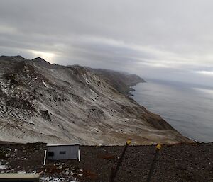 View from ‘the office at Mt Jeffryes shows the snow covered slopes of the island escarpment rising up from the ocean. A solr panel can be seen in the left foreground.