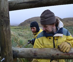 Dean having a go at the drilling into the big cross poles of the new fence while Billy holds the pole in place