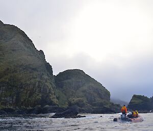 A view of the impressive rugged slopes and craggy rocky outcrops of Brothers Point from a IRB. A second IRB with three crew is in the foreground