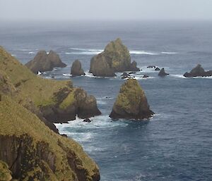 The rugged steep slopes of the escarpment meet with the sea in the southern part of the west coast. The jagged peaks of large rock stacks can be seen just offshore