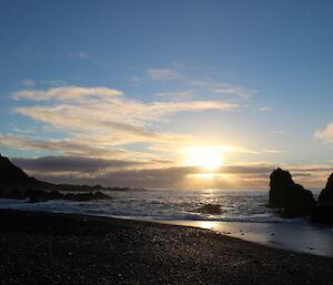 View from Green George beach at sunrise. A colourful sunrise with clouds as the sun rises above the beach bordered by rocks