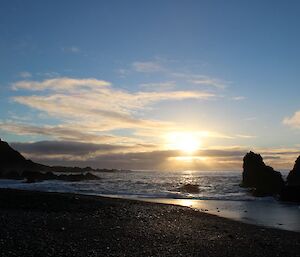 View from Green George beach at sunrise. A colourful sunrise with clouds as the sun rises above the beach bordered by rocks