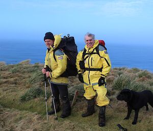 Nick, Tony in their yellow wet weather gear and Waggs, the black labrador on the Doctors track. The ocean can be seen in the background