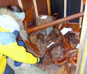 And back in storage. Patty places a small rusted item inside a wooden storage crate which already contains many other items, including an anchor.