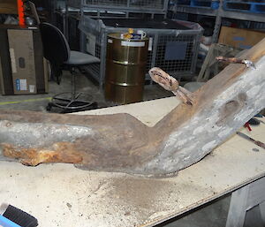 Carefully cleaned. A large timber cross member, possibly from an old ship, is carefully cleaned with a brush. The metal braces will get a coat of preservative
