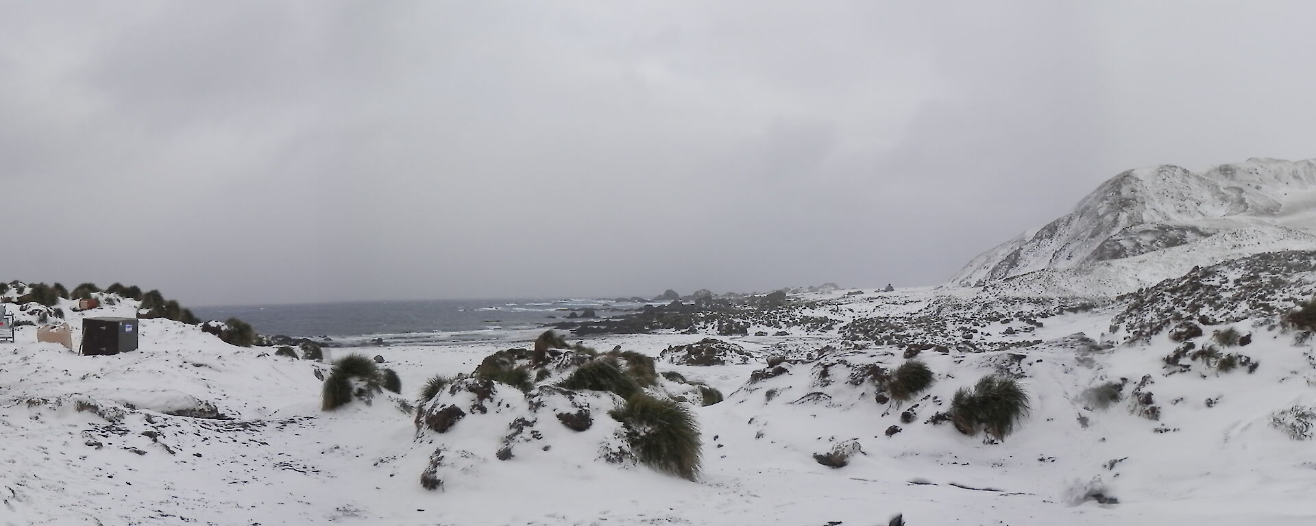 Panorama of a snow covered Bauer Bay, with the hut in the left of picture, the bay in the middle and the slopes of the escarpment on the right