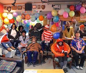 Fifteen of the expeditioners all dressed up in fancy dress for the all station meeting (on Marty’s Birthday). There are many coloured balloons decorating the room with the letters ‘Marty’ written across five of them