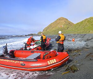 Beach landing at Brothers Point — the three boats on the grey sandy beach with Greg, Mark and Josh tending the boats and Brothers Point hut in the distant background up on a hill that slopes up from the beach