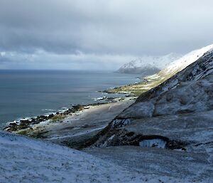 Looking south from a high vantage point on the Jessie Niccol track towards Waterfall Bay and Lusitania Bay. The landscape is covered in snow and the ocean can be seen on the left