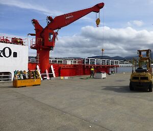 Our gear (in a cage pallet) being loaded by a bright red coloured crane onto L'Astrolabe, which is tied up at Macquarie four wharf