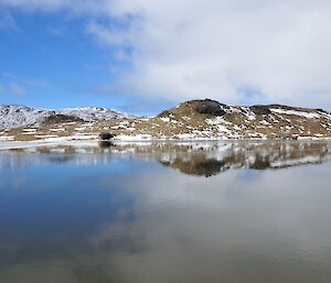 Depth measuring of Lake Emerald by Dominic in the small inflatable dingy. With very light winds the lakes surface reflects the snow covered hills and the partly cloudy sky.