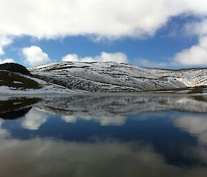 Emerald Lake on a light wind day so the water reflects the snow covered hills and the patchy cloud filled sky. This is the lake from which we take the sediment cores