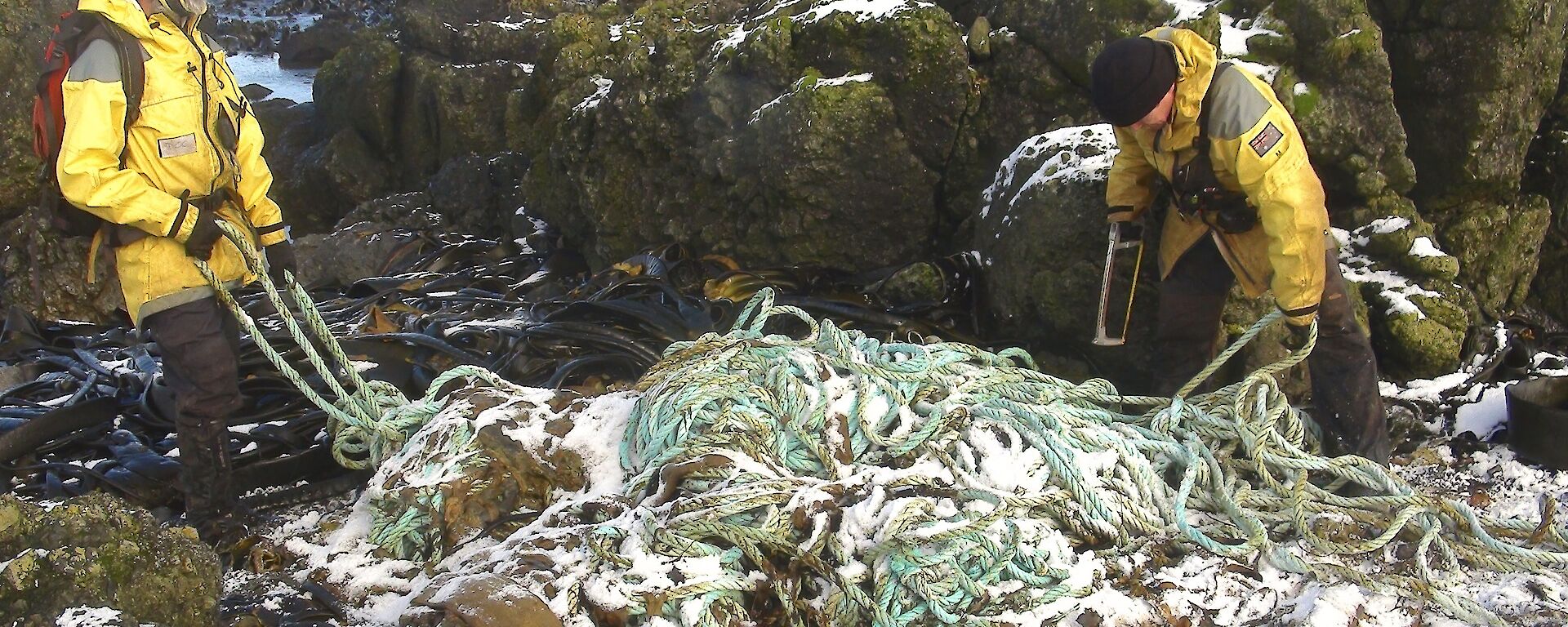 Where to start? Clive and Chris are at either end of the large pile of rope, trying to decide on the best way to untangle it. There is a light covering of snow on the rope and the rocky outcrops in the background