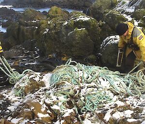 Where to start? Clive and Chris are at either end of the large pile of rope, trying to decide on the best way to untangle it. There is a light covering of snow on the rope and the rocky outcrops in the background