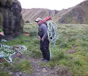 Chris showing how to look like a packhorse, loaded with rope. A side on view shows Chris’s pack heavily loaded with rope, which is dangling over the sides of the pack