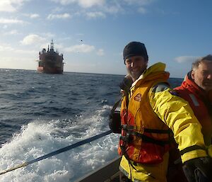 Arriving at Macca in March 2012. Steve dressed in wet weather gear and wearing a life jacket, stands on the deck of a LARC which is taking him from the Aurora Australis, in the background, to the shores of the island