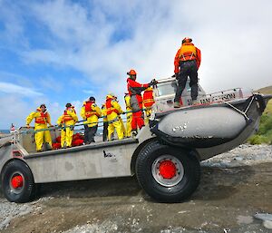 Arrival of the summer expeditioners at Landing Beach, all dressed in their yellow weather proof gear on the LARC ‘Ian Allison". The LARC has just come ashore. There are also four crew on the LARC