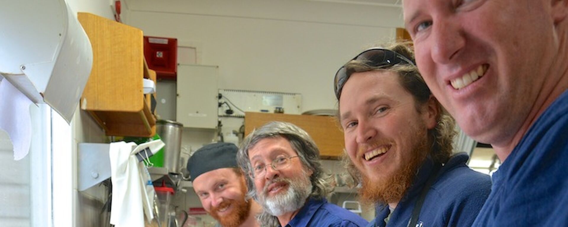 Four expeditioners: Jimmy, Clive, Aaron and Goldie standing by the kitchen sink peeling prawns for Christmas