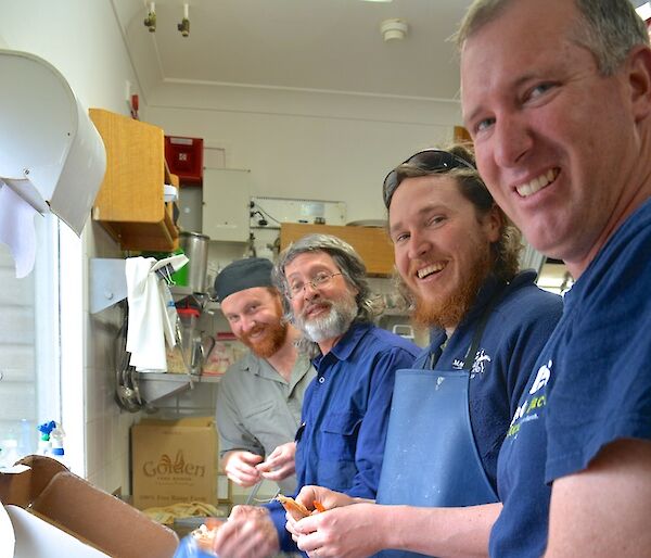 Four expeditioners: Jimmy, Clive, Aaron and Goldie standing by the kitchen sink peeling prawns for Christmas