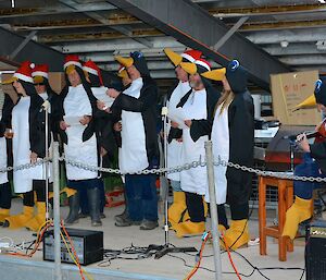 Expeditioners dressed in penguin costumes sing Christmas carols Christmas Eve
