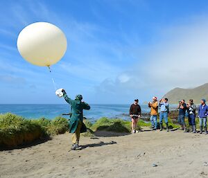 Expeditioner Vicki releases weather balloon with attached Ozone sonde Christmas morning while other expeditioners look on.