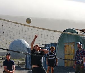 Expeditioners at the net with volleyball in the air during volleyball game