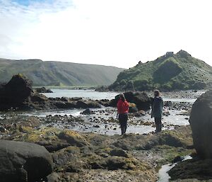 Jess and Dean, standing by the waters edge on the rocky shore of Garden Cove, looking for suitable sampling sites