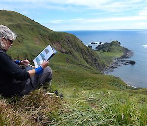 Jenny, sitting amongst the tussock on the ridge overlooking Hurd Point, assessing photo-monitoring sites on the steep slopes