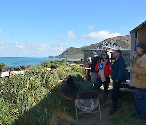 View of the BBQ and eight Australia Day revellers outside the boat shed. The view is to the south with the ocean to the left and the Nuggets in the distant background