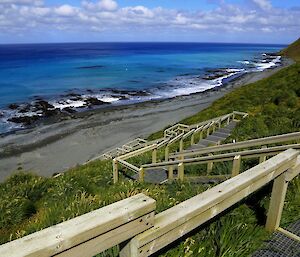 View from Razorback Ridge lookout. In the foreground is the wooden steps that lead up to the lookout, with the vivid azure blue ocean in the background and the east coast escarpment in the left of the picture