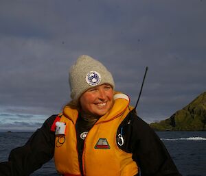 Jaimie driving one of the IRB’s. We see the top half of her. She is wearing a grey beanie with a Australian Antarctic Program badge. She is also wearing a bright yellow PFD (personal floatation device)