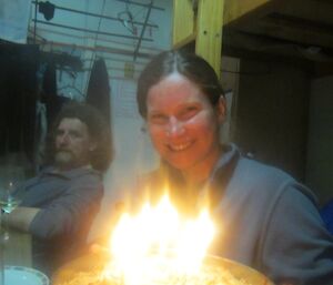 At Bauer Bay — Karen with her second birthday cake. The cake is still in a cake tin. You can see fellow MIPEP team member, Billy, in the background