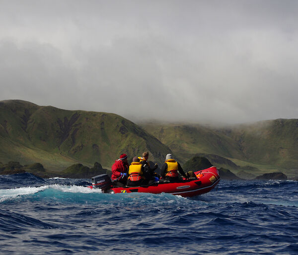 Cruising down the west coast. Image taken from an IRB with one of the other IRB’s in the foreground with four people on board. The rugged coast and green slopes of the escarpment are in the background