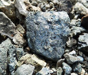 Macro image of a small rock that has blue flecks of lichen on its surface