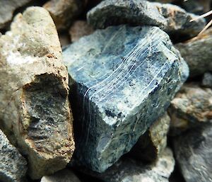 Green pinstripe. A macro image of a small rock that is greeny-blue in colour and has fin veins of white through it