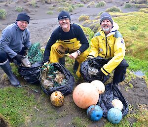 Chris, Barry and Clive with the marine debris they picked up along the east coast south of Cormorant Point. There are four black plastic bags in front of the them, filled with green fishing line, bits of plastic, plastic bottles and several different shaped and coloured fishing floats