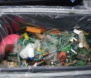 Nearly full cage pallet of marine debris including plastic bottles, rope and styrofoam.