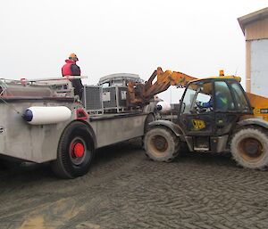 The JCB Loadall telescopic handler is seen lifting a cage pallet from the deck of the LARC