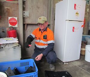 A ranger is seen checking the rodent trap and bait taken from the cage pallet