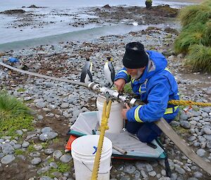 An expeditioner connects the refuelling hose on the beach