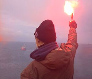 An expeditioner holds a burning flare