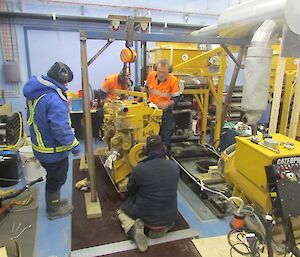 Four expeditioners supervise lifting engine