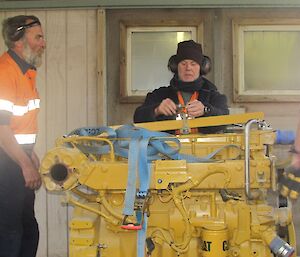 Two expeditioners disconnect the lifting slings from the engine