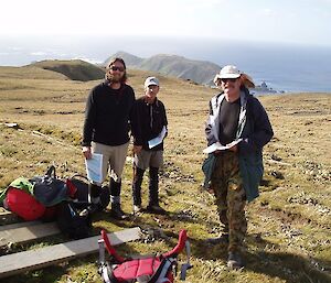 Three expeditioners in the field holding maps