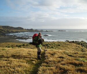 Expeditioner walking down track into beautiful bay