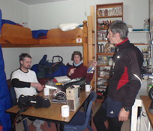 Three expeditioners are seen inside the field hut