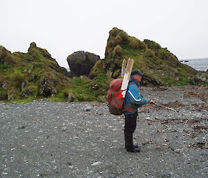 An expeditioner on the beach with a back pack full of track markers