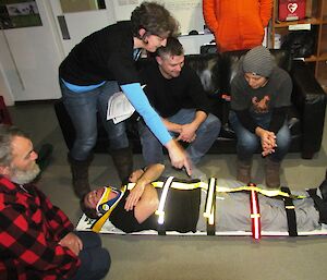 Expeditioners being shown how to put a patient on a spinal board