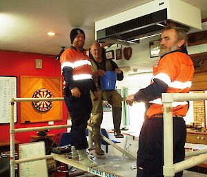 Three expeditioners installing ceiling heater