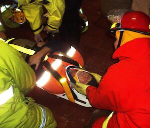 Expeditioner on stretcher surrounded by fire team during training exercise